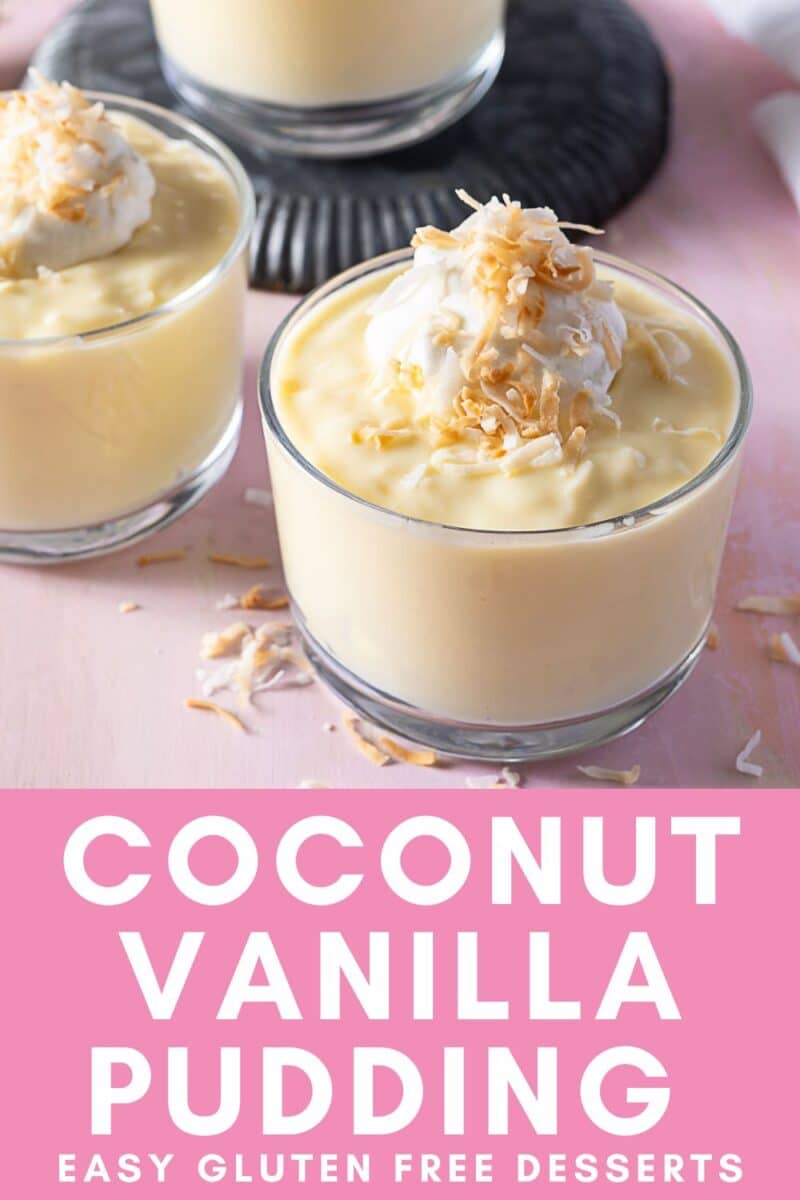 Two glass cups filled with coconut pudding and vanilla, topped with whipped cream and toasted coconut flakes, rest on a pink surface.