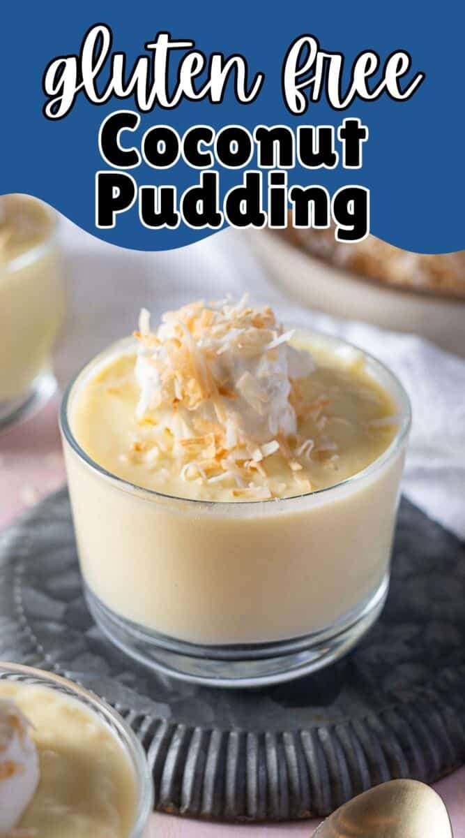 A glass cup of coconut pudding sits topped with whipped cream and toasted coconut flakes, all placed on a textured coaster for an elegant finish.