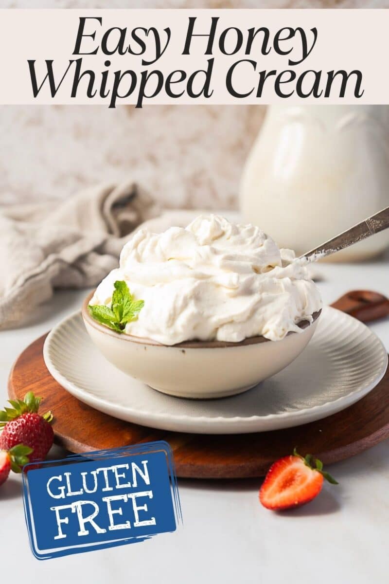 A bowl of mascarpone whipped cream with honey and a hint of mint sits on a plate with strawberries.