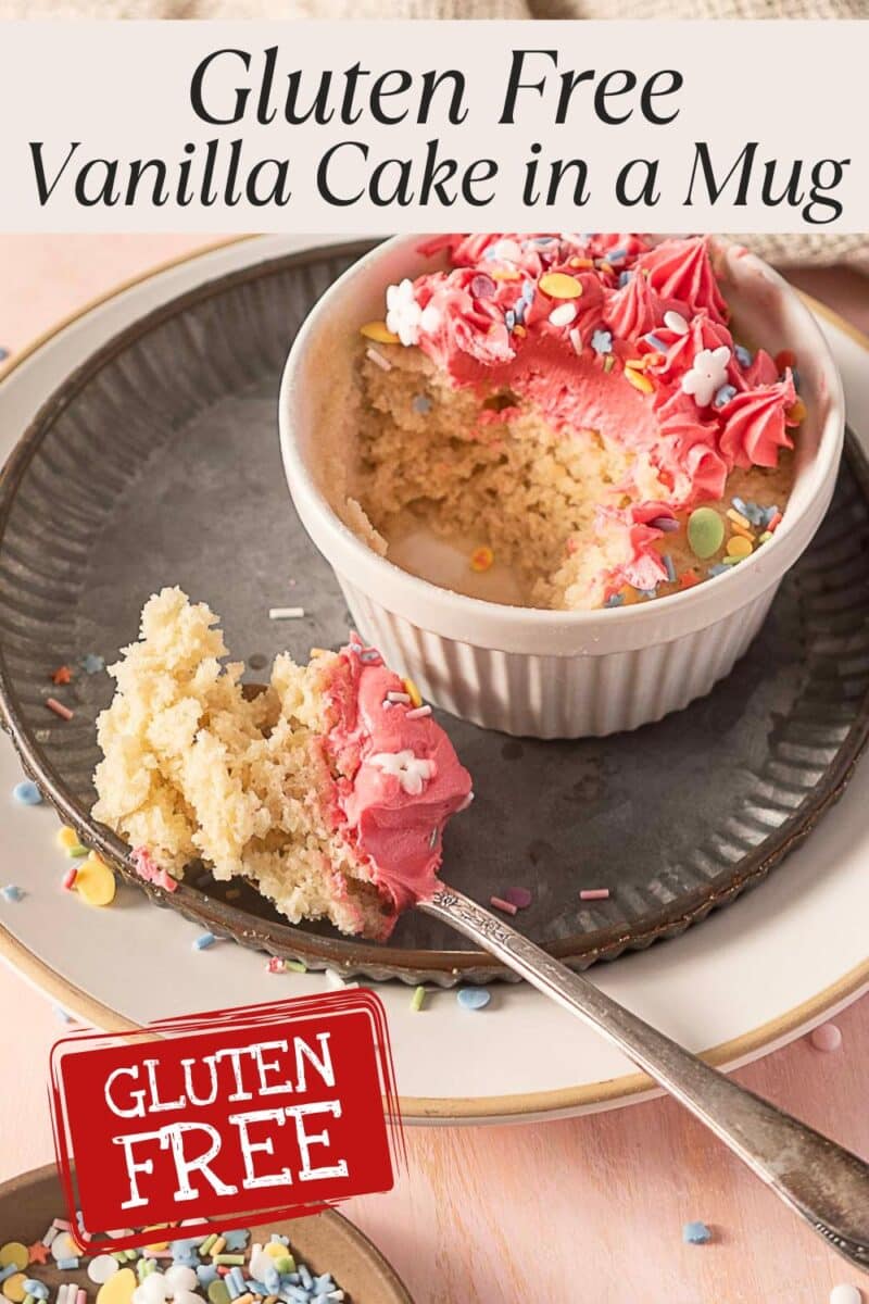 A small vanilla cake with pink frosting and sprinkles is served in a white ramekin on a plate, with a spoonful removed. Text reads "Gluten Free Vanilla Cake in a Mug" and "Gluten Free.