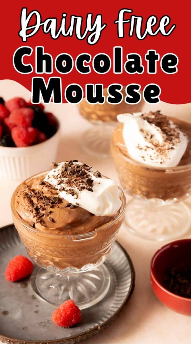 Three glass cups of dairy free chocolate mousse topped with whipped cream and chocolate shavings, with fresh raspberries and a bowl of mixed berries nearby.