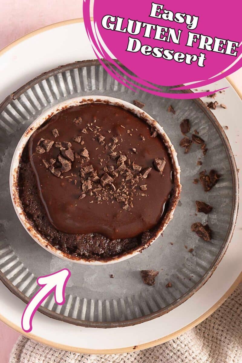 A small bowl of gluten free chocolate mug cake topped with chocolate sauce and shavings sits on a gray plate, with "Easy Gluten Free Dessert" written in a pink banner at the top.