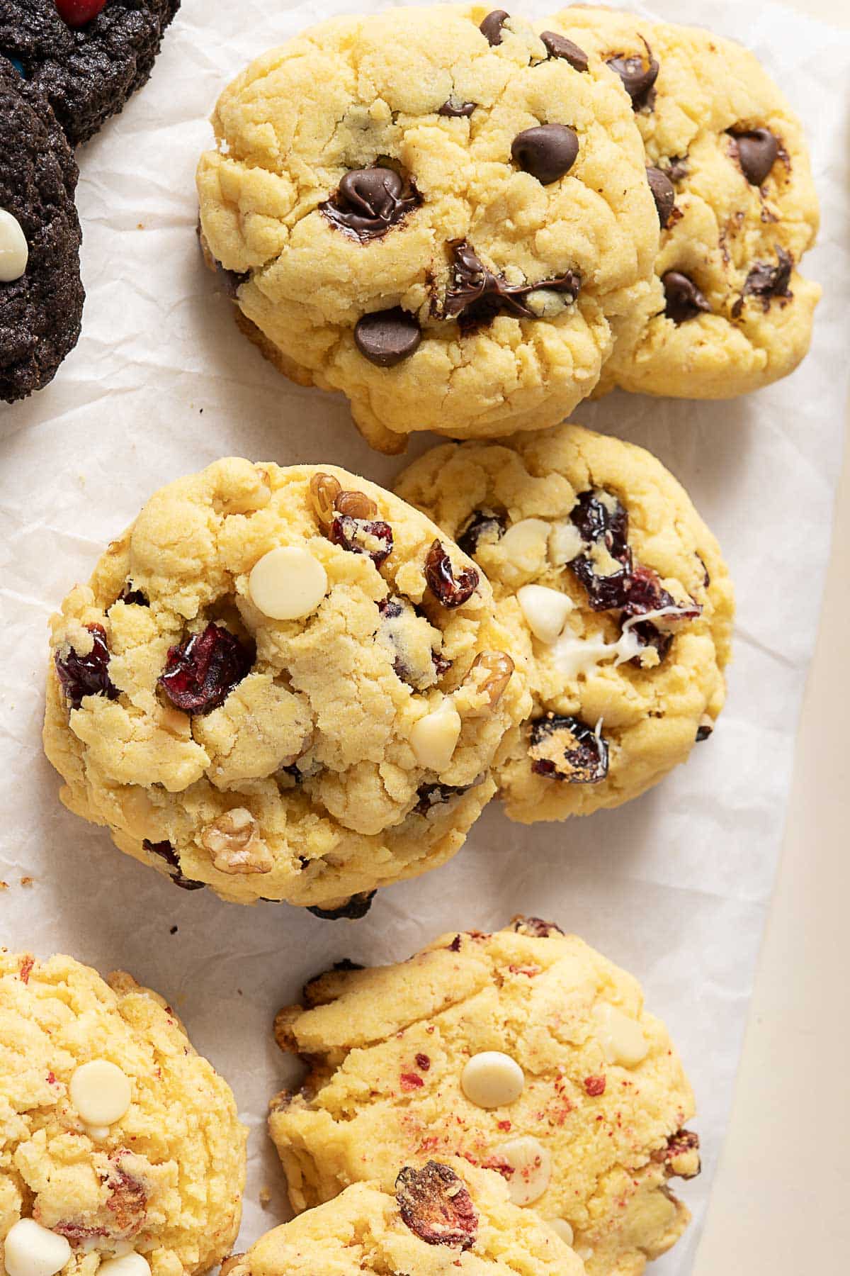 A close-up of several chocolate chip and white chocolate cranberry cookies arranged on parchment paper.