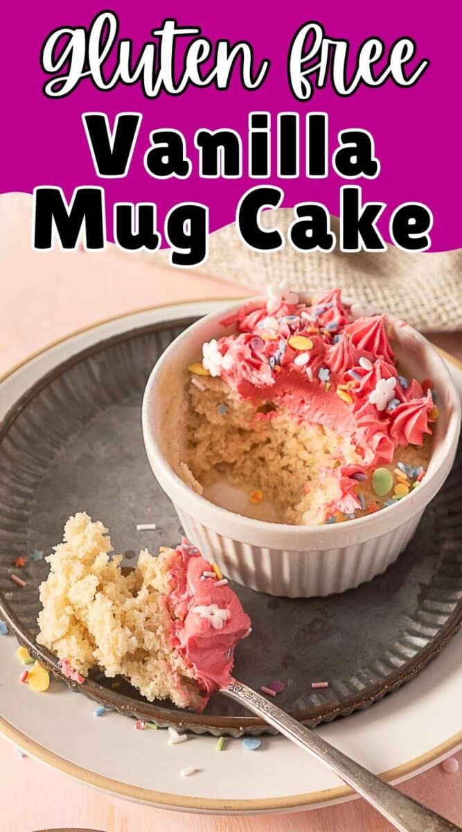 A small ramekin with gluten-free vanilla mug cake topped with pink frosting and sprinkles, served on a plate with a spoonful of cake beside it.