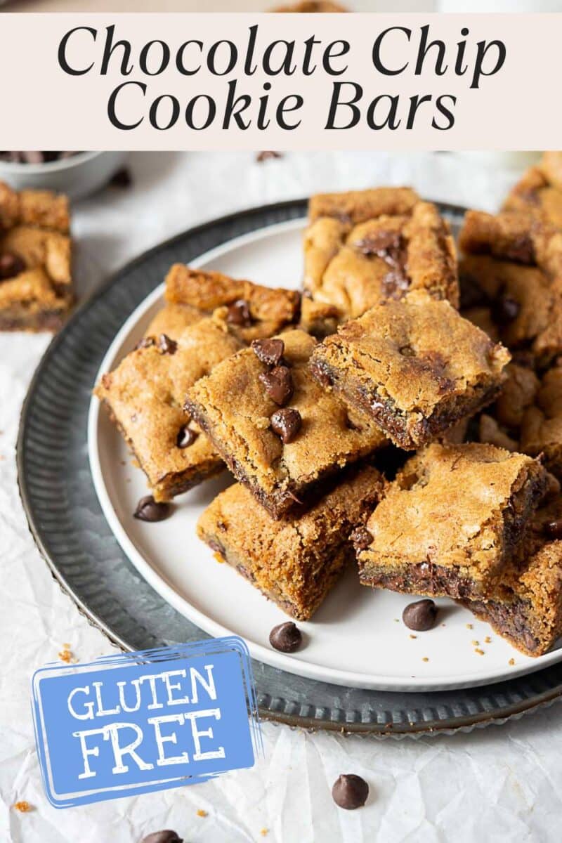 A plate of gluten free chocolate cookie bars is displayed, with several bars stacked on a white plate and loose chocolate chips scattered around.