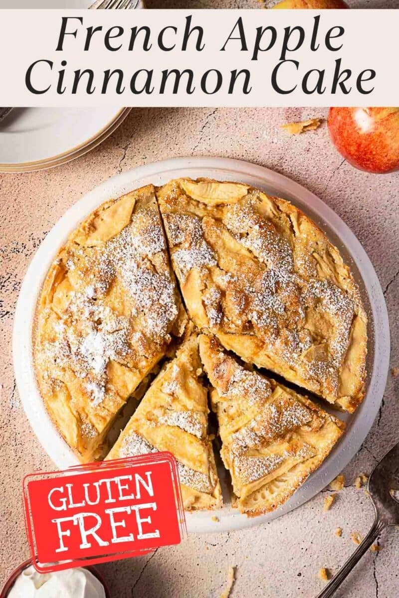 A round gluten free apple cake, sliced and dusted with powdered sugar, is labeled as such. An apple and a bowl with cream are nearby.