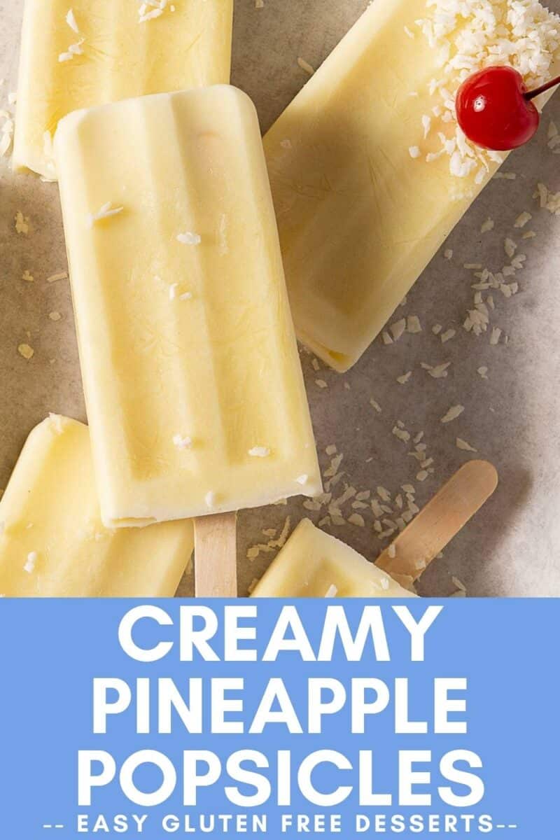Four creamy pina colada popsicles with coconut flakes and a cherry rest on parchment, with text reading "Creamy Pineapple Popsicles - Easy Gluten Free Desserts.