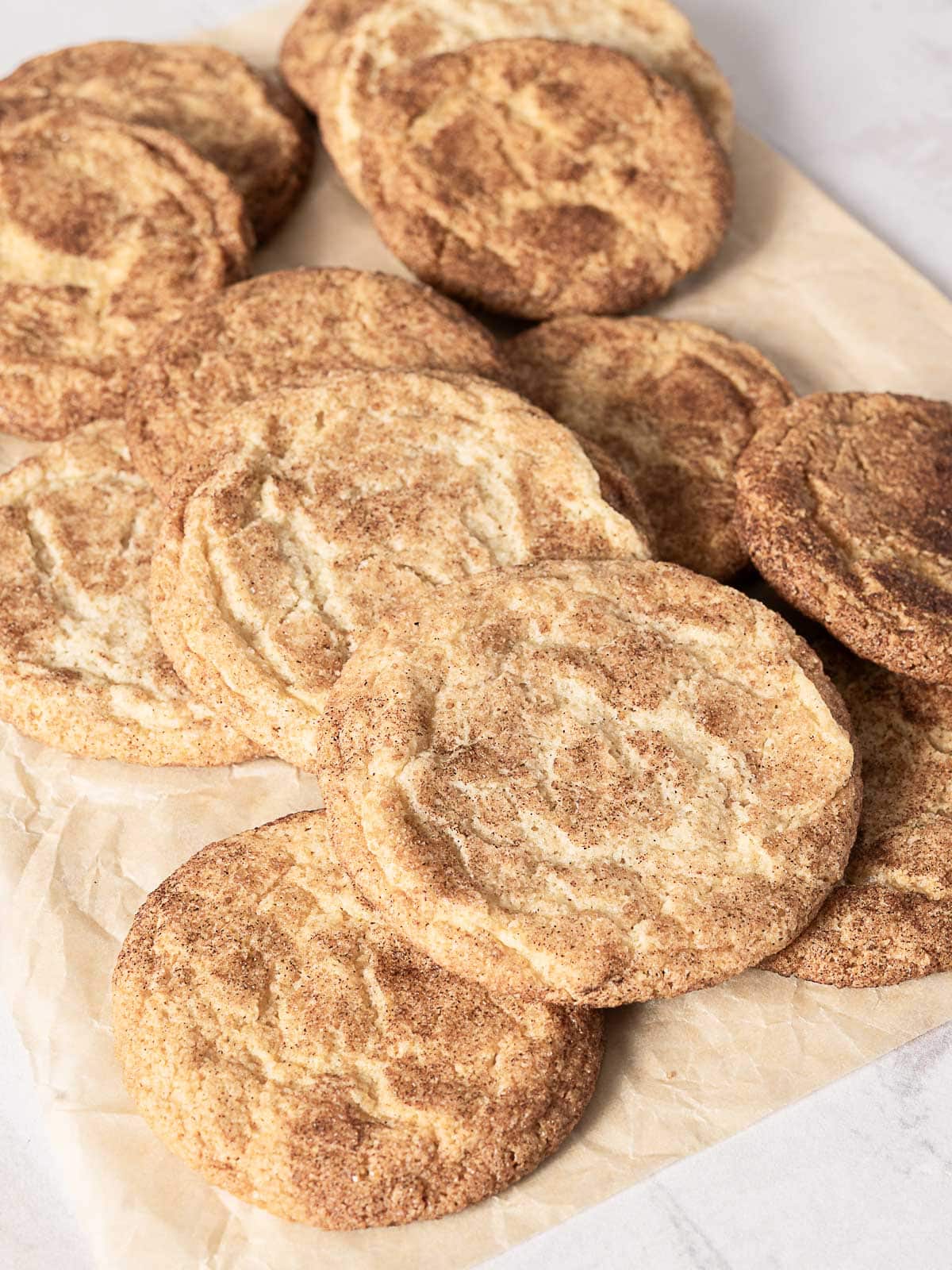 A batch of snickerdoodle cookies arranged on a sheet of parchment paper.