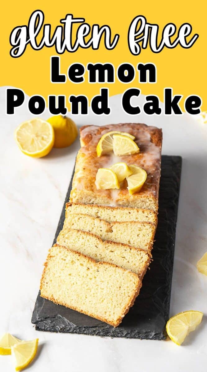 A gluten free lemon pound cake with glaze and lemon wedges on top, sliced and beautifully arranged on a black slate serving board surrounded by fresh lemon pieces.