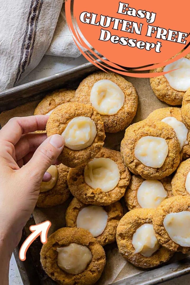 A hand holds a gluten-free thumbprint cookie with white filling over a tray of similar cookies; text reads "Easy GLUTEN FREE Dessert" – perfect for fans of gluten free pumpkin cookies.