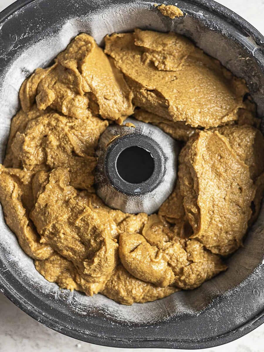 A bundt pan filled with thick, light brown cake batter, evenly spread but not yet baked.