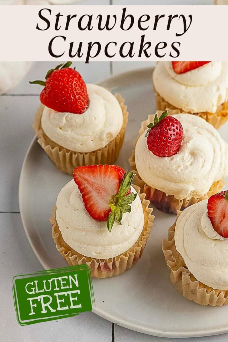 A plate of gluten free strawberry cupcakes topped with white frosting and fresh strawberry halves. Text reads "Strawberry Cupcakes" and "Gluten Free.