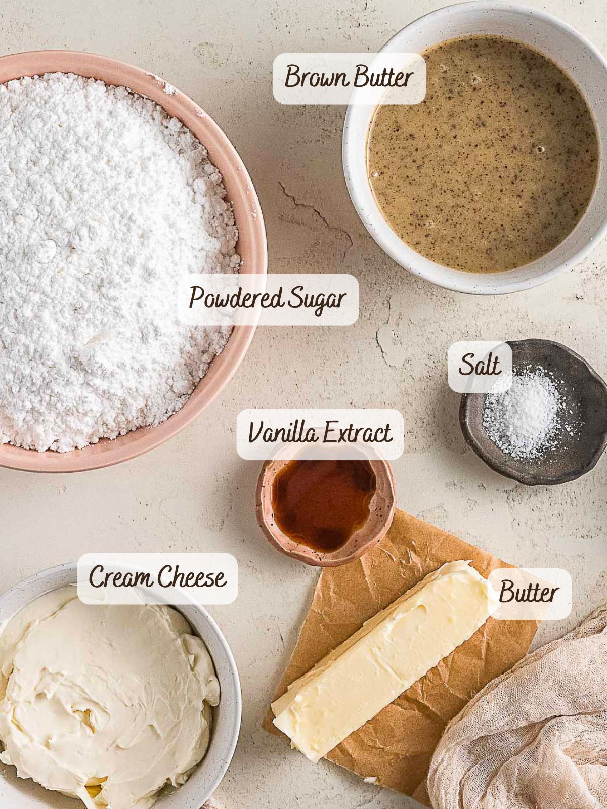 Bowls of powdered sugar, brown butter, cream cheese, and salt, plus a stick of butter and vanilla extract, are neatly arranged-ready to be whipped into a rich Brown Butter Cream Cheese Frosting.