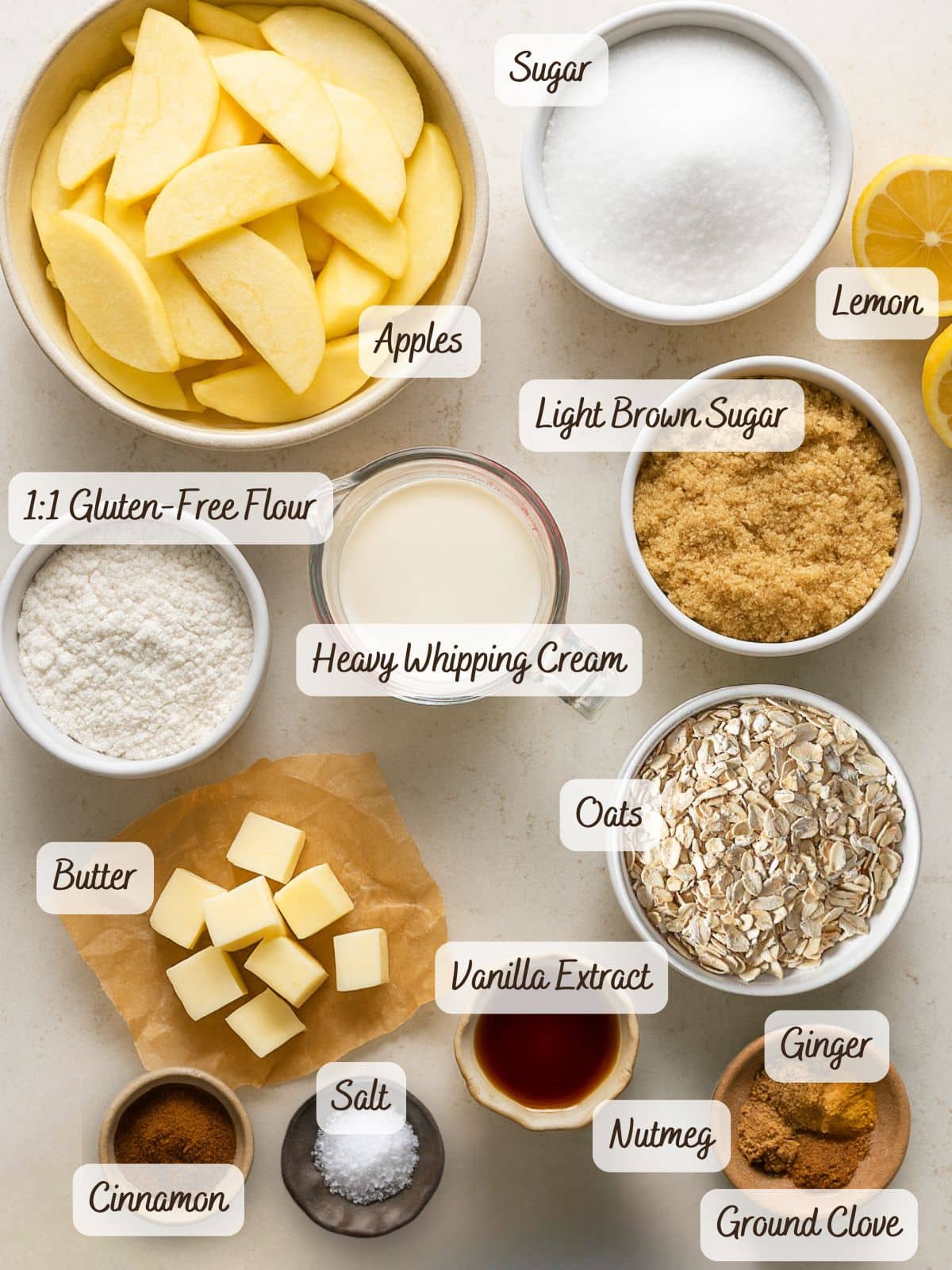 Overhead view of labeled ingredients for a gluten free caramel apple pie, including apples, sugars, lemon, gluten-free flour, heavy cream, oats, spices, vanilla, butter, and salt, all arranged neatly on a surface.