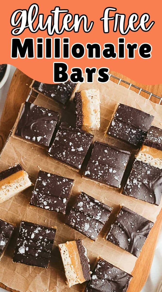 Sliced gluten free millionaire shortbread bars with chocolate topping and sea salt flakes are arranged on parchment paper atop a wire rack.