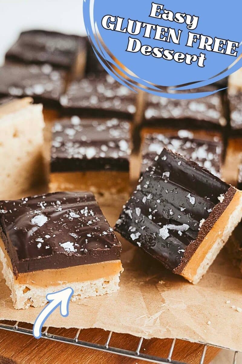 Squares of gluten free millionaire shortbread with a cookie base, caramel middle, and chocolate top, sprinkled with sea salt, arranged on parchment paper. Text overlay reads, "Easy GLUTEN FREE Dessert.