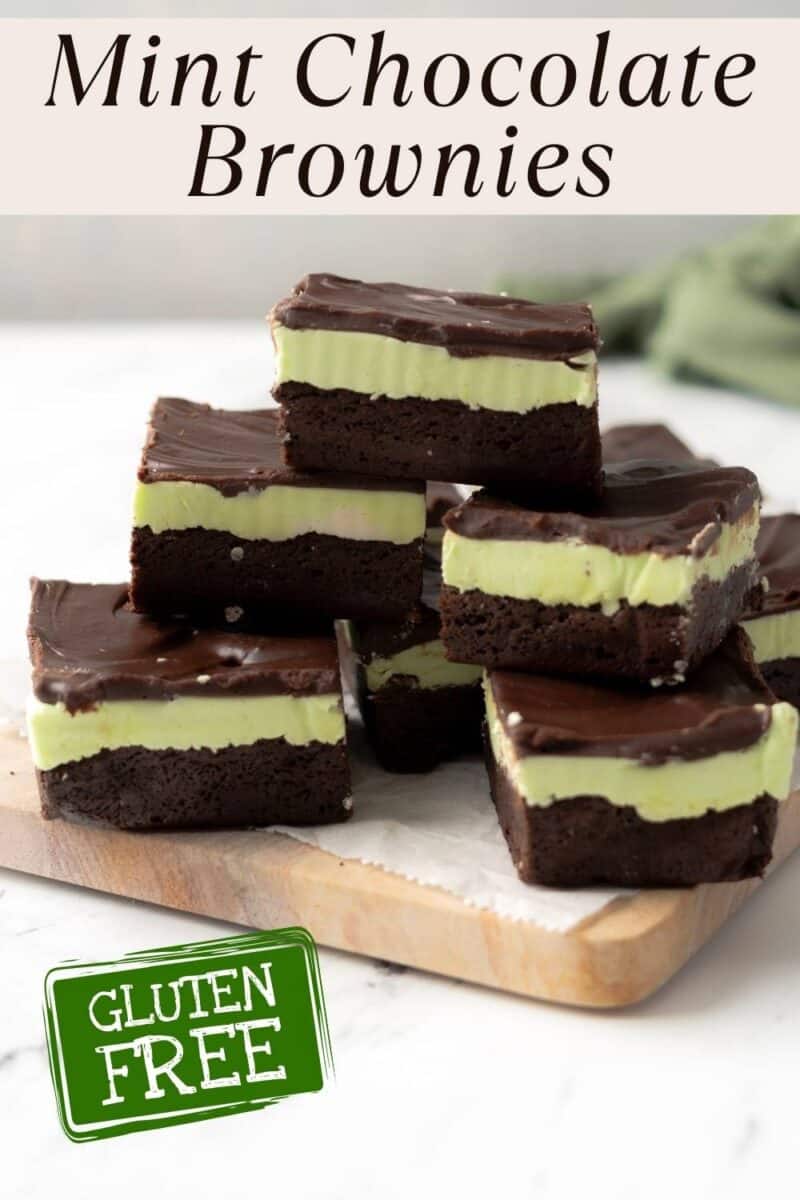 A stack of gluten free mint chocolate brownies with green mint and chocolate layers, arranged on a wooden board. A label reads "GLUTEN FREE.