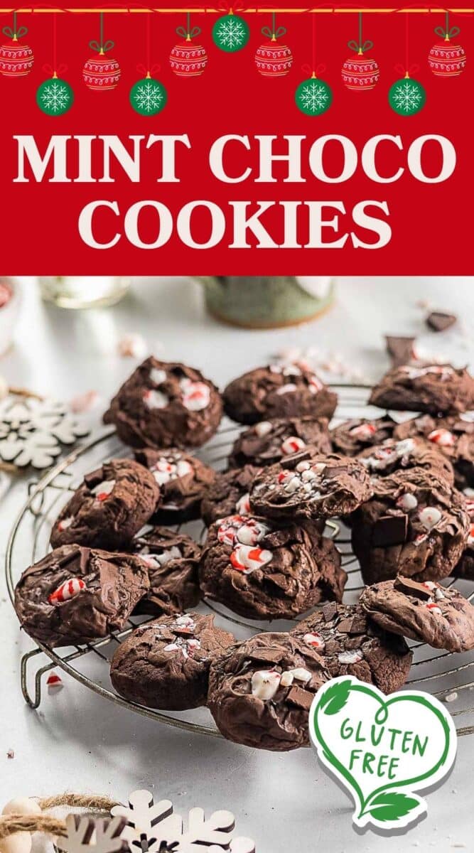 A cooling rack holds several Gluten Free Chocolate Peppermint Cookies topped with crushed candy canes, with a "gluten free" label in the foreground and holiday decorations in the background.