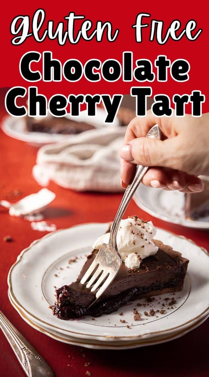 A hand holds a fork slicing into a piece of rich chocolate tart topped with whipped cream on a white plate