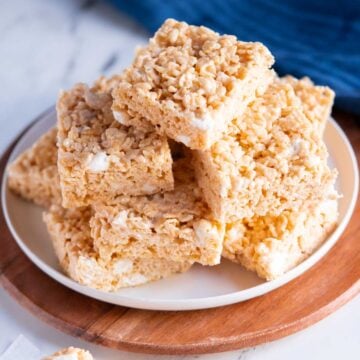 A plate stacked with homemade gluten free rice krispy treats, showing their light golden color and marshmallow texture.
