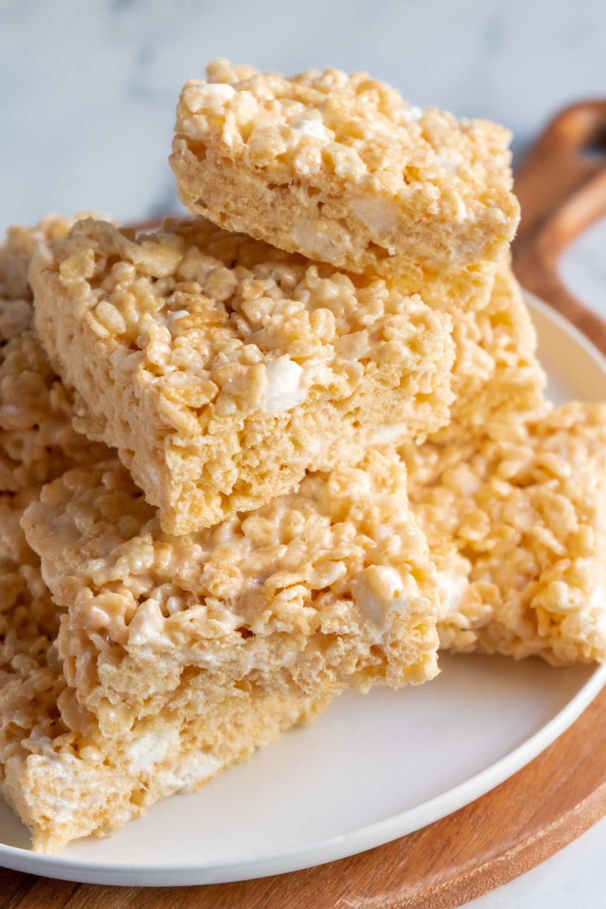 A plate with several stacked gluten free Rice Krispy treats, showing their crispy cereal texture and marshmallow filling.