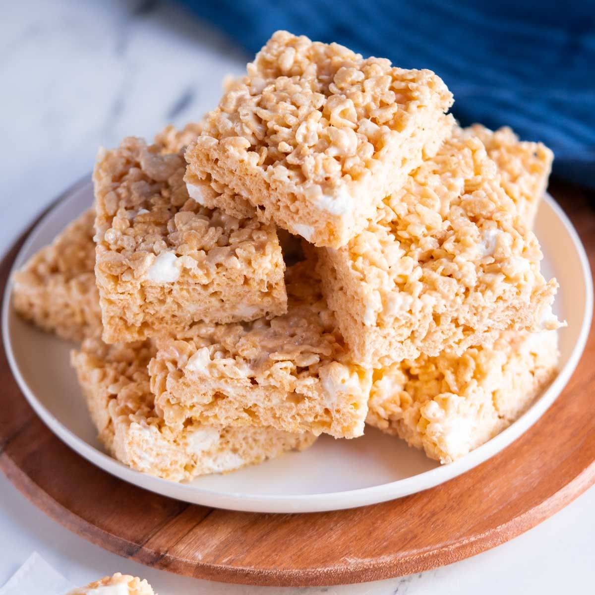 A plate stacked with homemade gluten free rice krispy treats, showing their light golden color and marshmallow texture.
