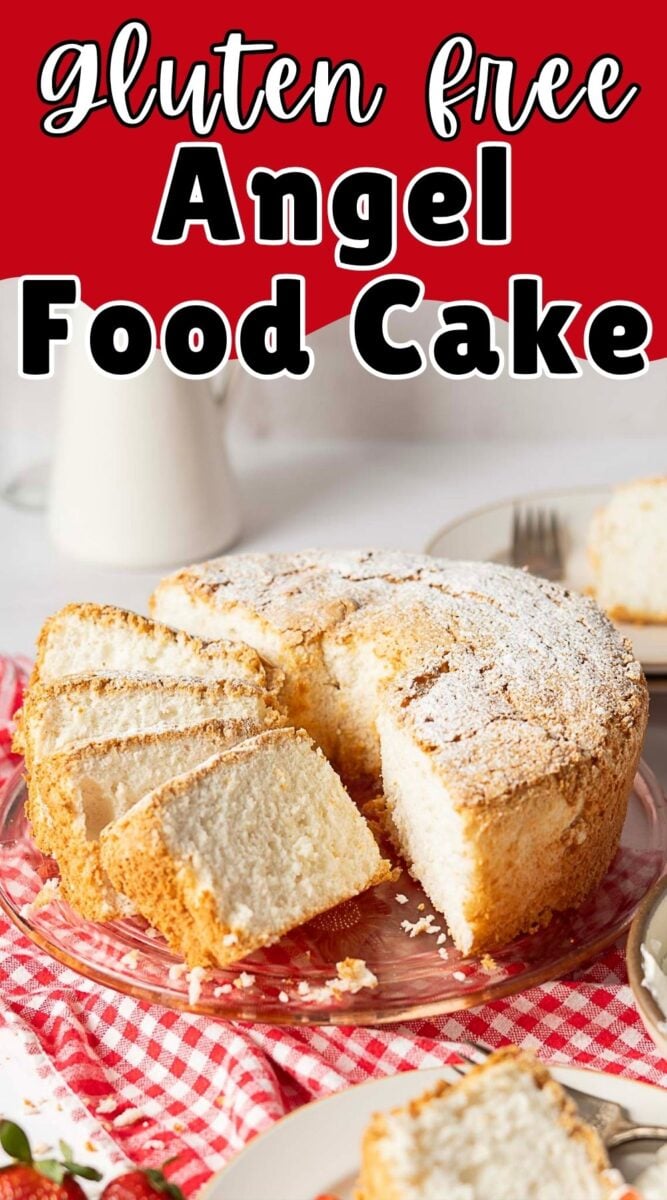 A sliced Gluten Free Angel Food Cake on a glass plate, topped with powdered sugar and set on a red and white checkered cloth.