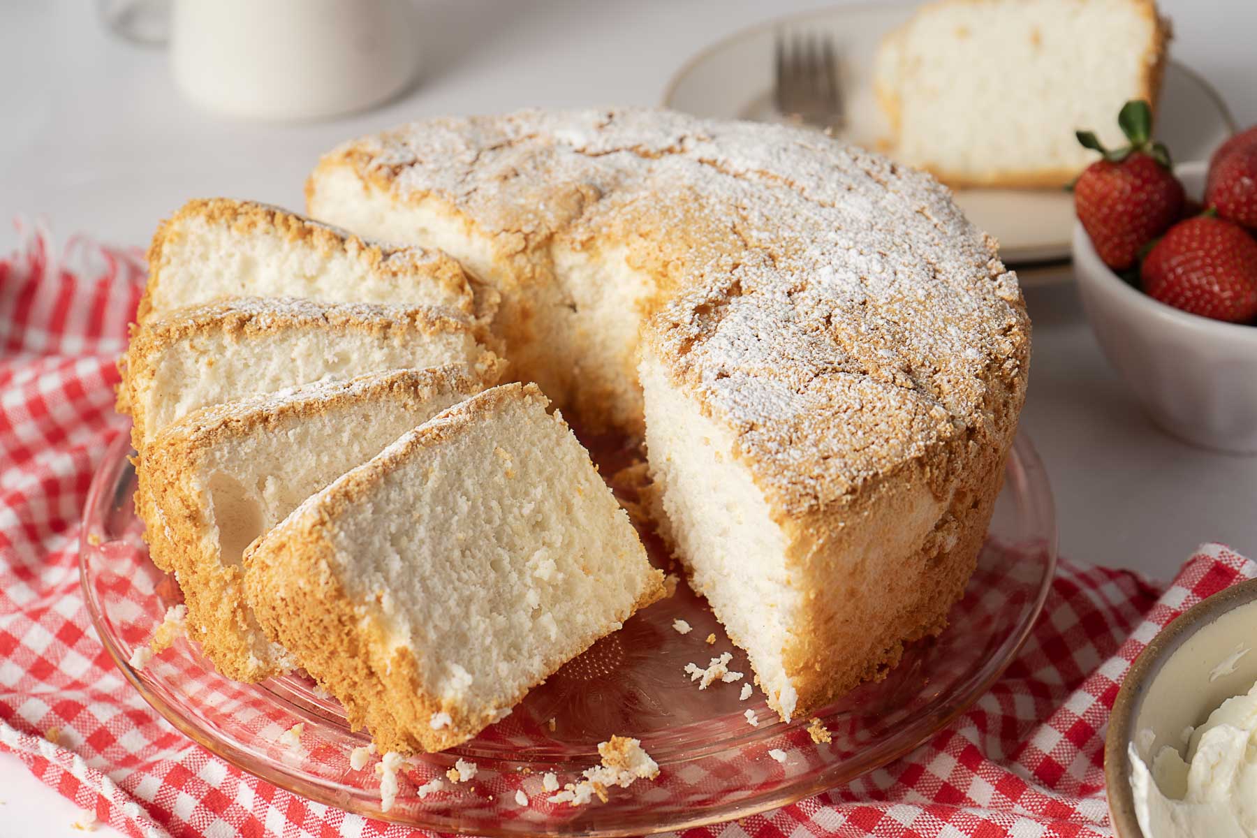 Sliced angel food cake on a glass cake stand. 