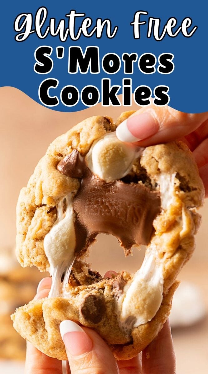 A person pulls apart a gluten-free s’mores cookie, revealing melted chocolate and marshmallow filling inside—an irresistible treat for anyone craving delicious gluten free cookies.