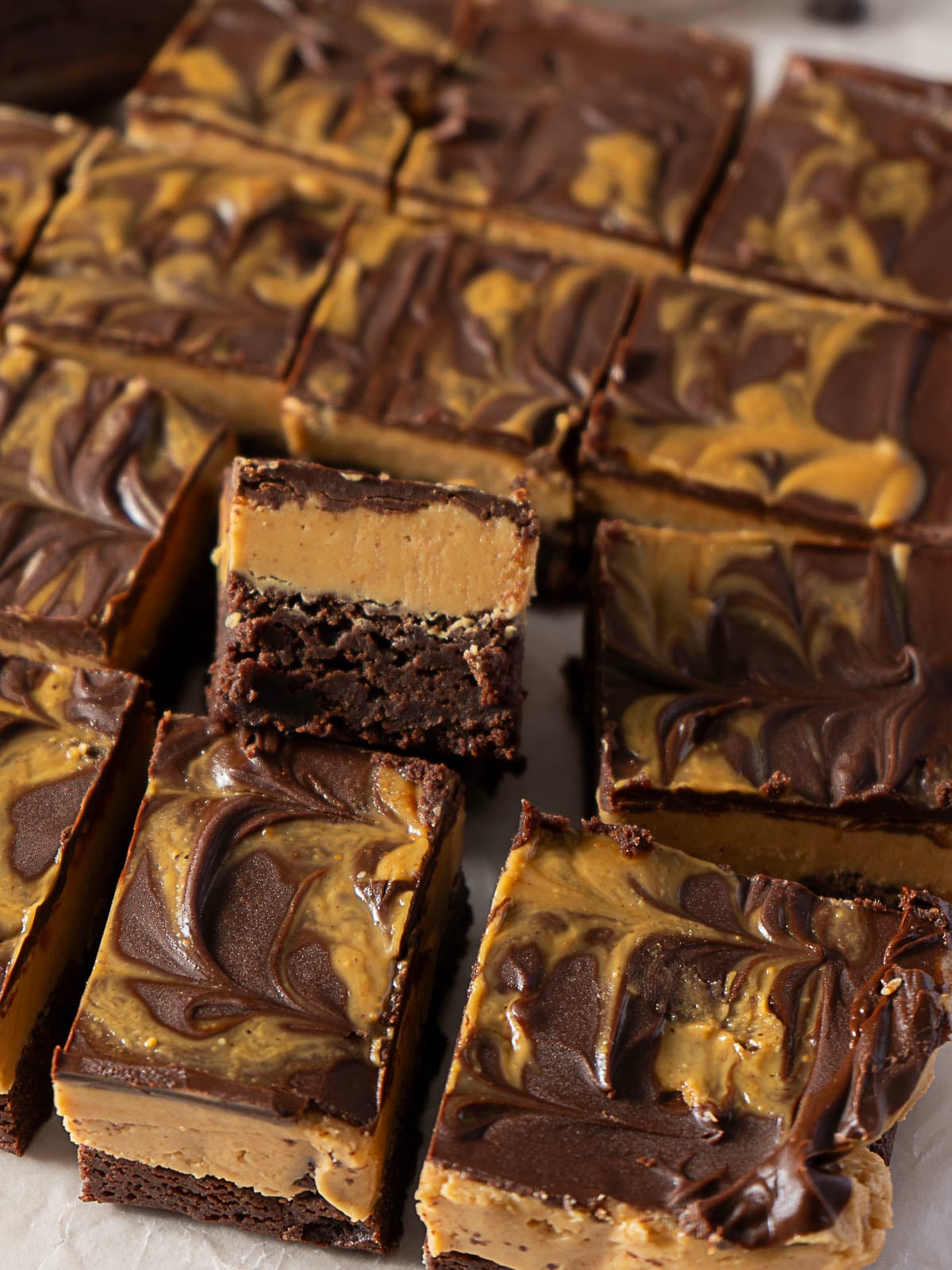 Rows of chocolate and peanut butter swirl brownies, with one brownie turned on its side to show the layered texture.