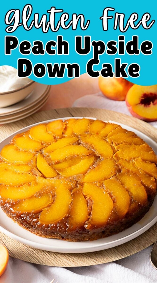 A gluten-free upside down cake on a white plate, topped with sliced peaches, with whole peaches and a bowl of whipped cream in the background.