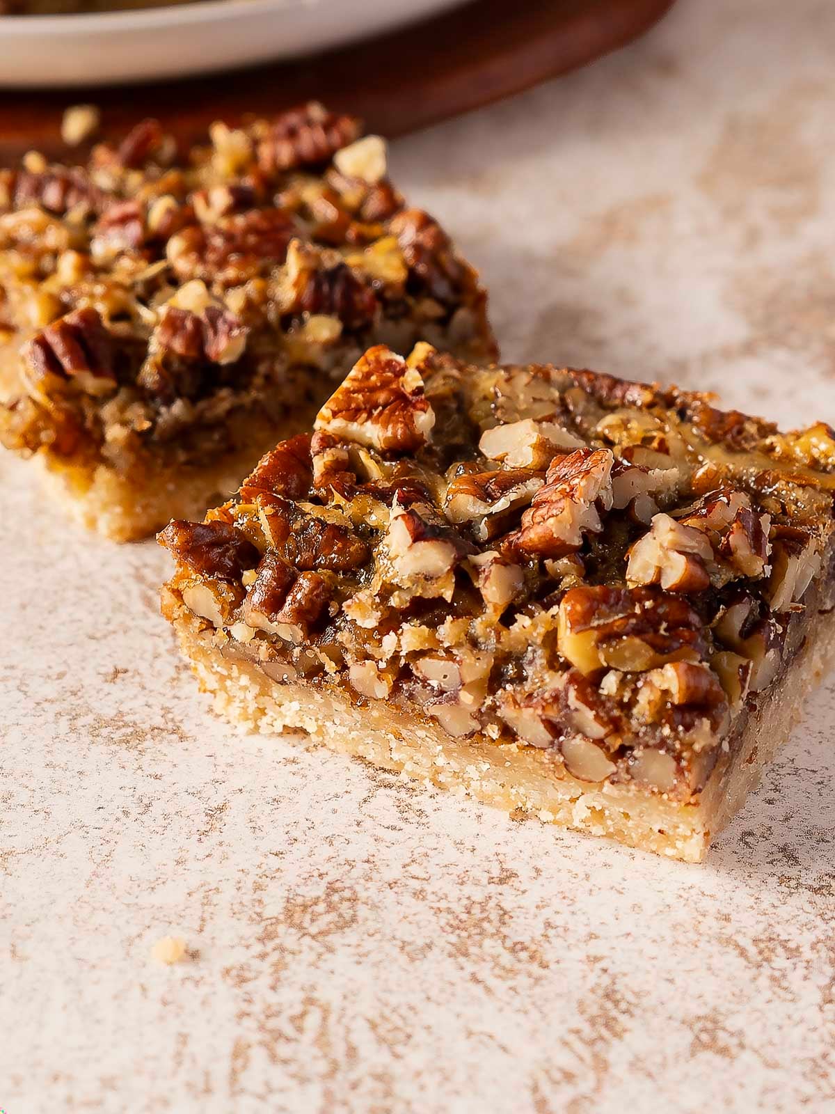 Two square pecan pie bars with a crust and a nutty filling.